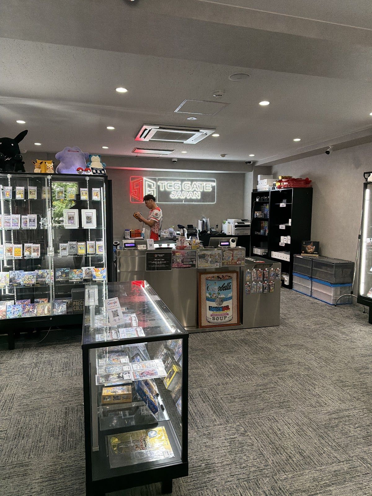 TCG GATE トレカゲート秋葉原本店の店内 — ネオンロゴとPSA鑑定カードのショーケース